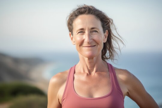 Portrait of smiling woman standing on beach in the sunshine looking at camera