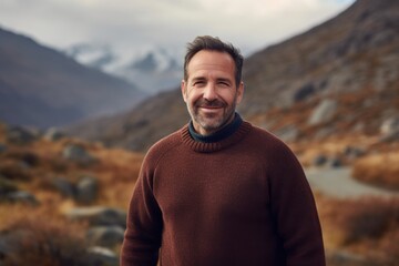 Handsome man in a brown sweater on the background of mountains