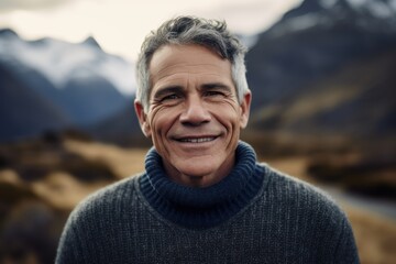 Portrait of smiling middle-aged man with grey hair against snowy mountains