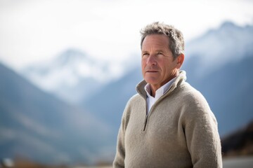 Portrait of a senior man in winter clothing against snow capped mountains