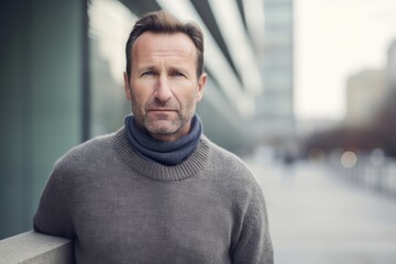 Portrait of a middle-aged man in a gray sweater in the city