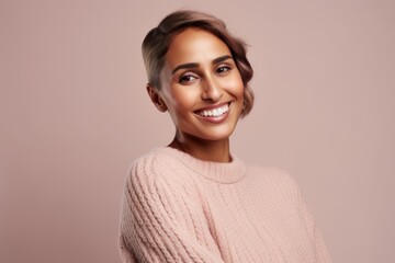 Fototapeta premium Portrait of a beautiful smiling young woman in a pink sweater.