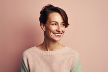 Obraz premium Portrait of a beautiful young woman smiling on a pink background.