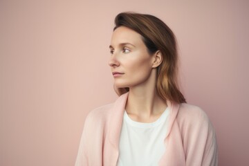 Fototapeta premium Portrait of a pensive young woman in a pink jacket on a pink background