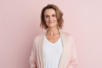 Fototapeta premium Portrait of a beautiful middle-aged woman in a pink jacket on a pink background