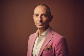 Obraz premium Portrait of a bald man in a pink suit on a brown background