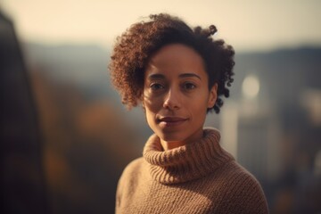 Portrait of a beautiful young african american woman with afro hairstyle, wearing brown sweater and looking at the camera.