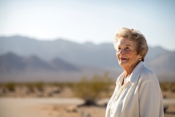 Fototapeta premium Portrait of happy senior woman standing in the middle of the desert