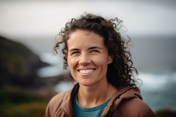 Portrait of smiling woman with curly hair looking at camera on beach
