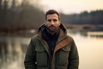 Portrait of a handsome bearded man in a green jacket with a hood
