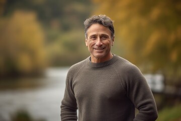 Handsome middle-aged man in a sweater standing by the river