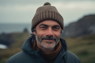 Portrait of a handsome middle aged man with grey beard wearing a warm hat and a blue jacket