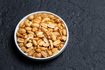 Pile of roasted peanuts on black background, space for text