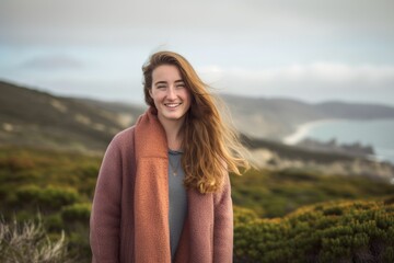 Fototapeta premium Portrait of a beautiful young woman smiling at the camera while standing on a hilltop.