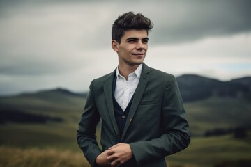 Handsome young man in a green suit on the background of the mountains