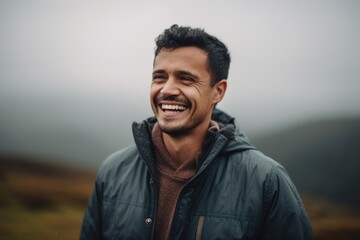 Portrait of a handsome young man smiling while standing in the mountains