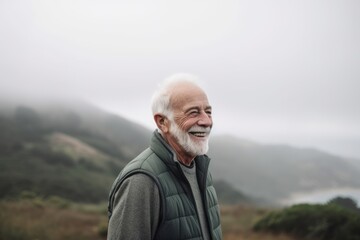 Naklejka na ściany i meble Portrait of senior man hiking in the mountains on a foggy day