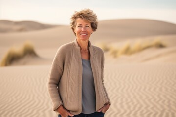 Fototapeta na wymiar Portrait of smiling senior woman standing in the middle of the desert