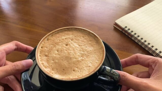 person holding a cup of coffee and spin it around because of curious, nervous, anxiety