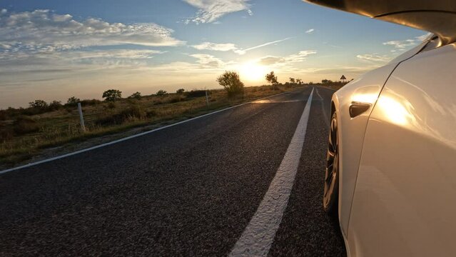 CLOSE UP: Driving through stunning Adriatic landscape in beautiful golden light. Car drive on winding asphalt road surrounded with green Mediterranean shrubs and meadows in warm morning sunrise light.