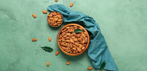 Bowls of almonds on green background, top view