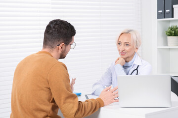 Obraz premium Doctor consulting patient at white table in clinic