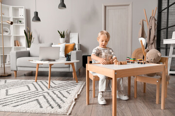 Cute little boy playing with wooden cubes at home