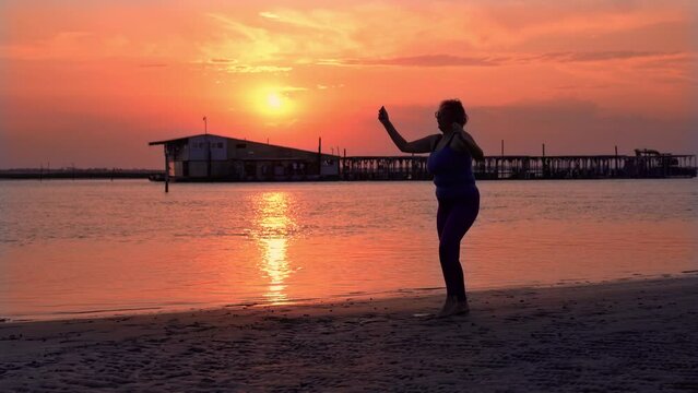 Silhouette of plump woman training on empty sea beach