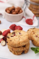 Cookies with freeze dried fruits, nuts and mint on white table, closeup