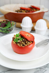 Delicious stuffed tomato with minced beef, bulgur and mushrooms on white marble table, closeup