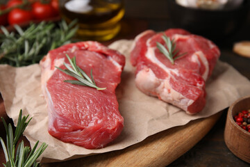 Fresh raw meat with rosemary on wooden table, closeup