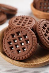Tasty chocolate sandwich cookies with cream on white wooden table, closeup