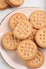 Tasty sandwich cookies with cream on white wooden table, top view