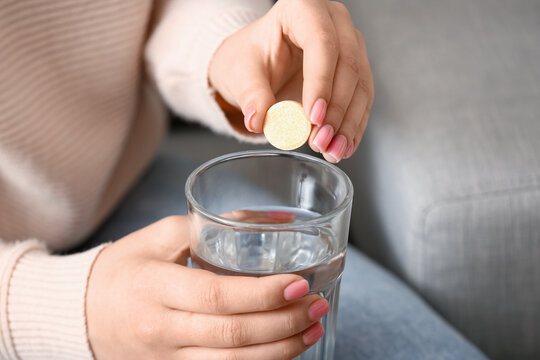 Woman Putting Effervescent Tablet Into Glass Of Water