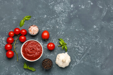 Composition with bowl of delicious tomato sauce and ingredients on grey grunge table
