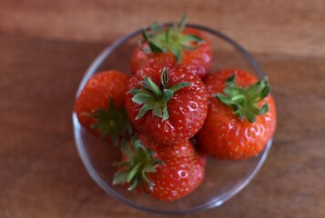 fresh ripe strawberries in a glass cup on a wooden table