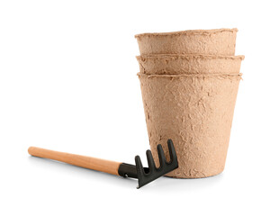 Peat pots and rake on white background
