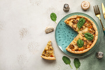 Mushroom pie with spinach leaves and cutlery on green grunge table