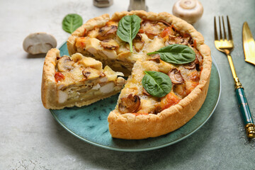 Mushroom pie with spinach leaves and cutlery on green grunge table