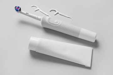 Electric toothbrush with paste and toothpicks on grey background