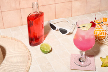 Fresh summer cocktail with lime and cherry on tile table near beige wall