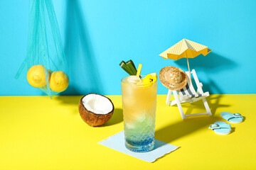 Fresh summer cocktail with lemon and flower on yellow table near blue wall