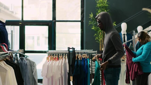 African american robber shoplifting clothes, running from modern boutique. Asian bodyguard catches thief at store door, threatens him with the police in shopping mall. Burglary concept