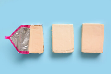 Processed cheese in foil on blue background