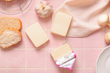 Processed cheese, bread and vegetables on pink tile background