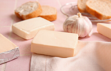 Processed cheese, bread and vegetables on pink tile background