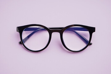 Stylish black eyeglasses on lilac background