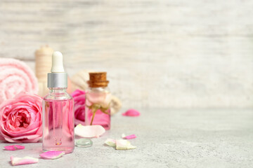 Fototapeta na wymiar Bottles of cosmetic oil with rose extract and flowers on white table