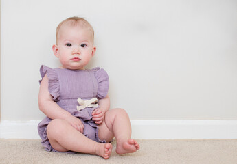 Cute Caucasian baby girl learning how to sit at 9 month old