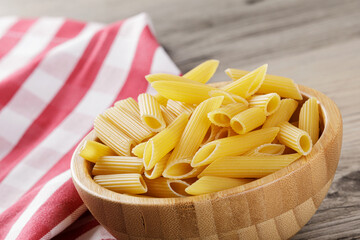 Raw Penne Rigate noodles isolated on a wooden background